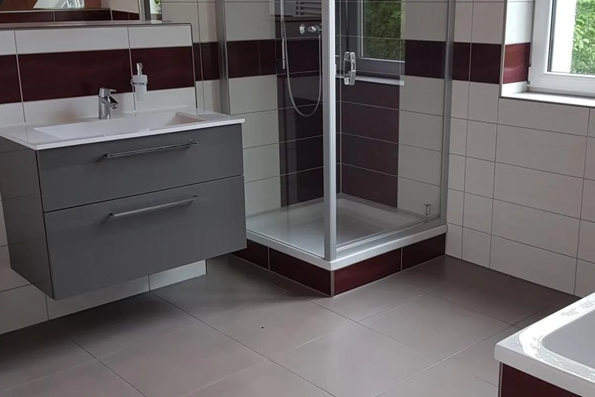 Badezimmer mit Waschtisch, Eckdusche und Badewanne, beige und bordeaux gefliest