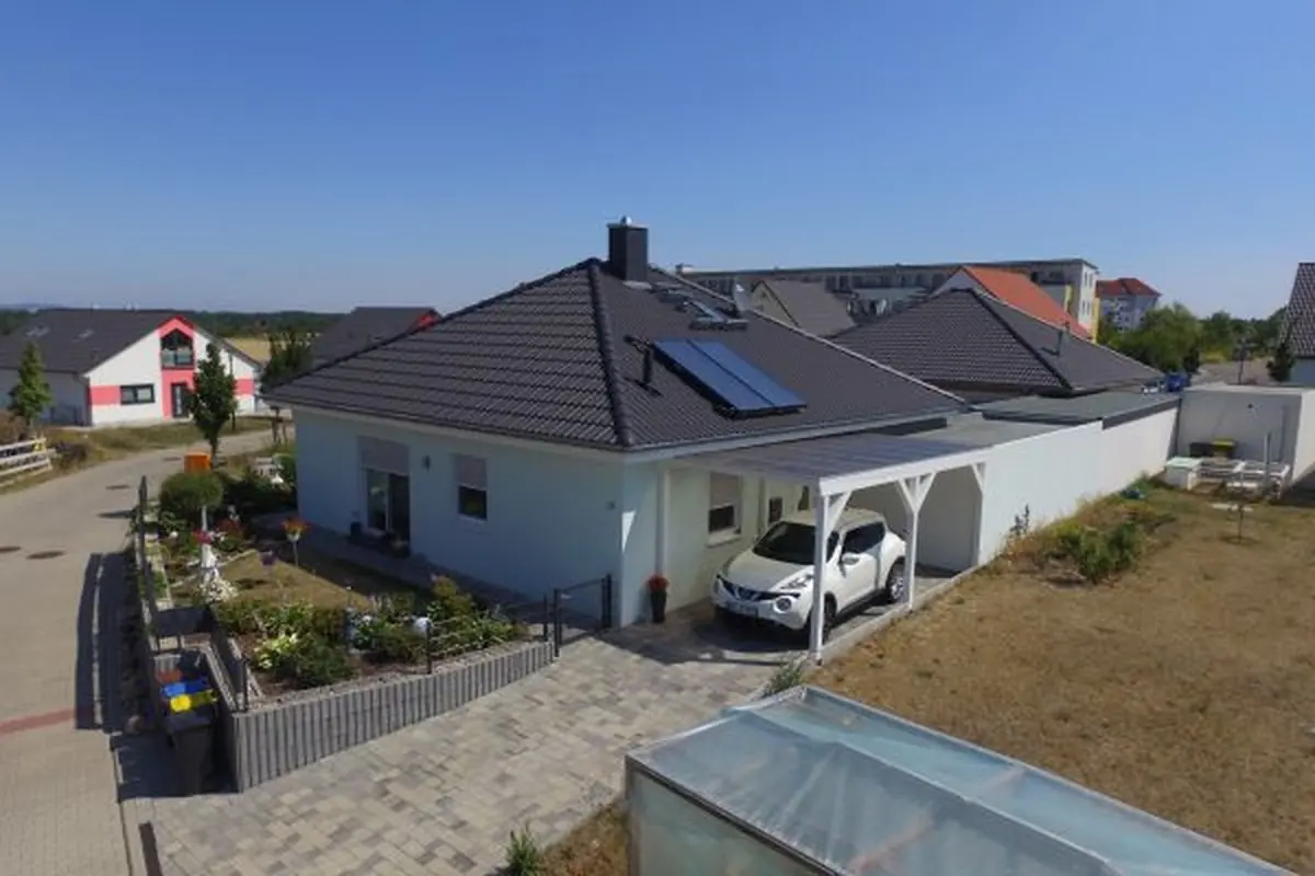 Luftaufnahme eines Bungalows mit dunklem Walmdach