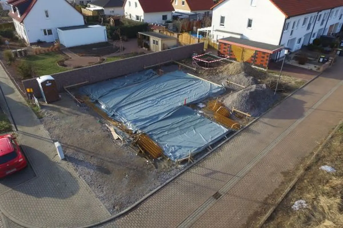Luftaufnahme einer Baustelle mit abgedeckter Bodenplatte