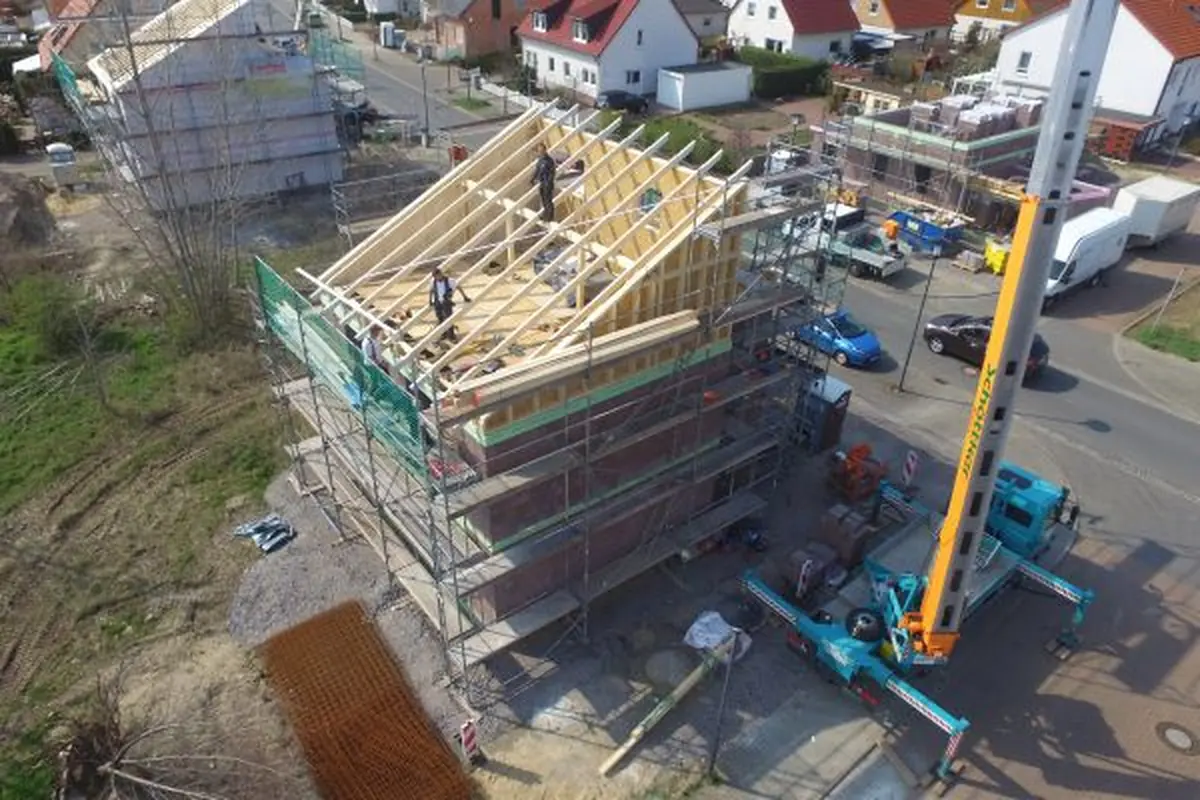 Luftaufnahme einer Hausbaustelle mit Gerüst und Kran