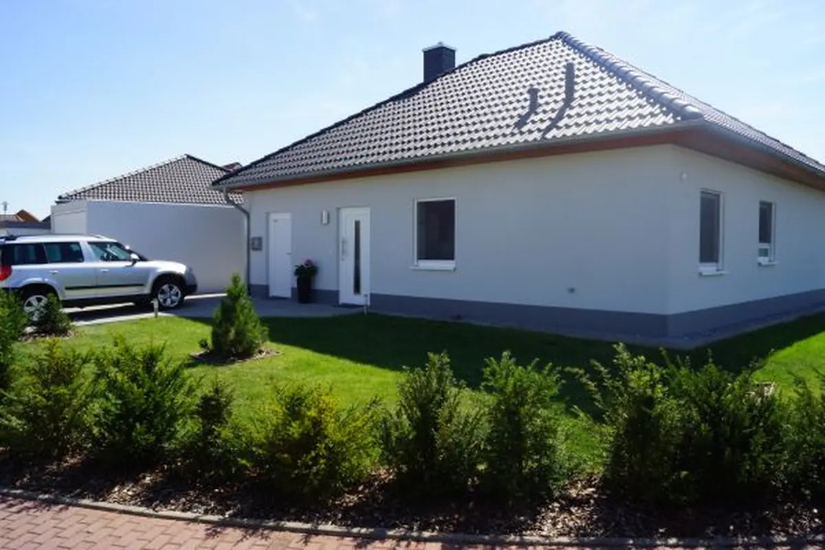 Bungalow mit dunklem Walmdach und Vorgarten