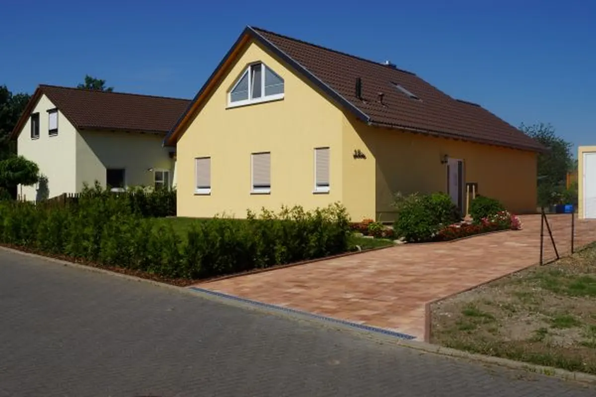 Einfamilienhaus mit gelber Fassade und Pflasterweg