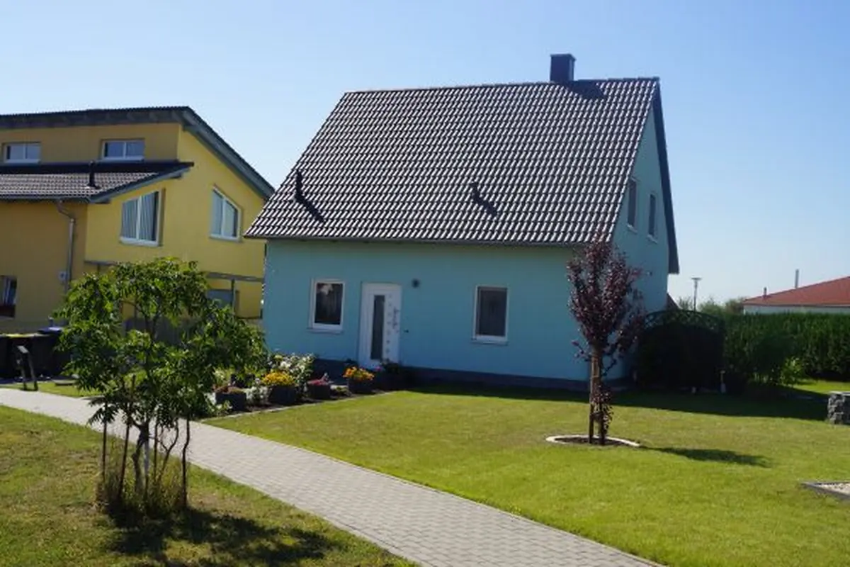 Einfamilienhaus mit hellblauer Fassade und rotem Dach