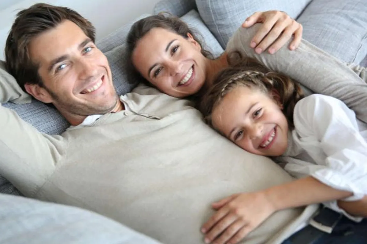 Familie mit Kind liegt entspannt auf dem Sofa